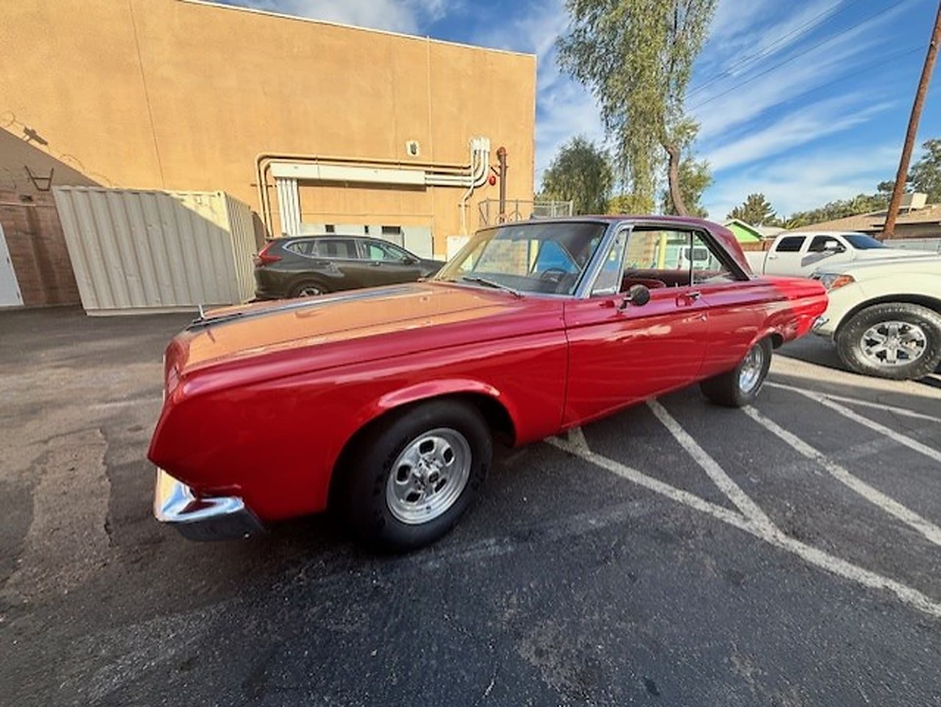 Red 1967 Dodge Dart GT convertible parked beside a tan building