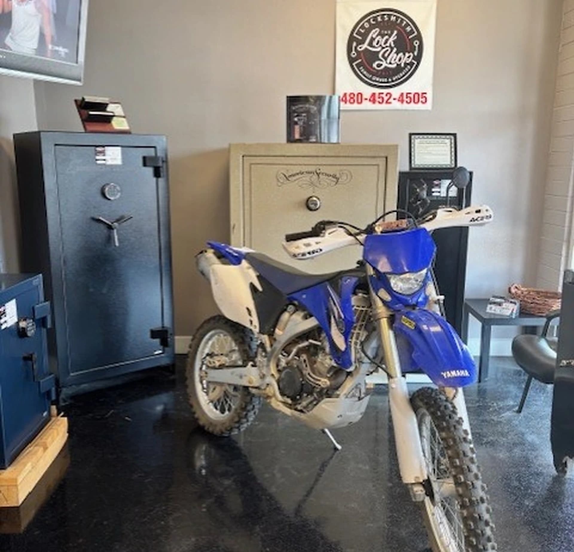 Blue dirt bike parked beside safes inside The LOCK Shop showroom