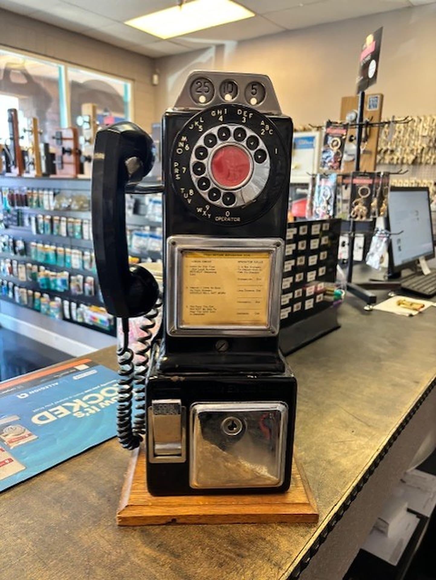 Vintage payphone on the shop counter with key blanks on the wall behind