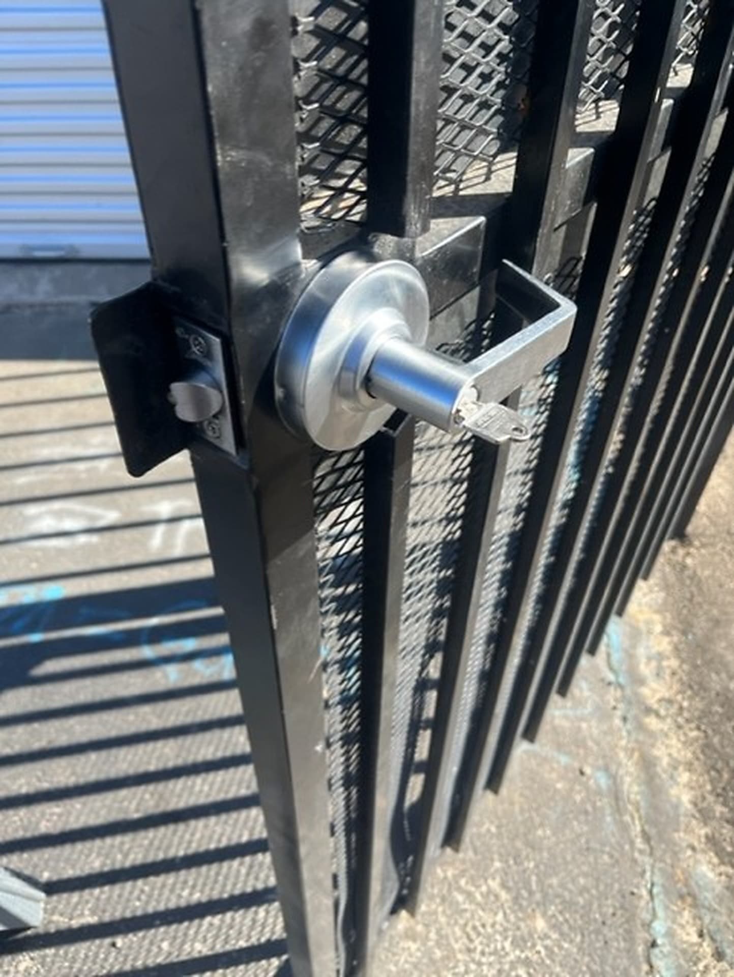 Lever handle and keyed cylinder on a black metal gate