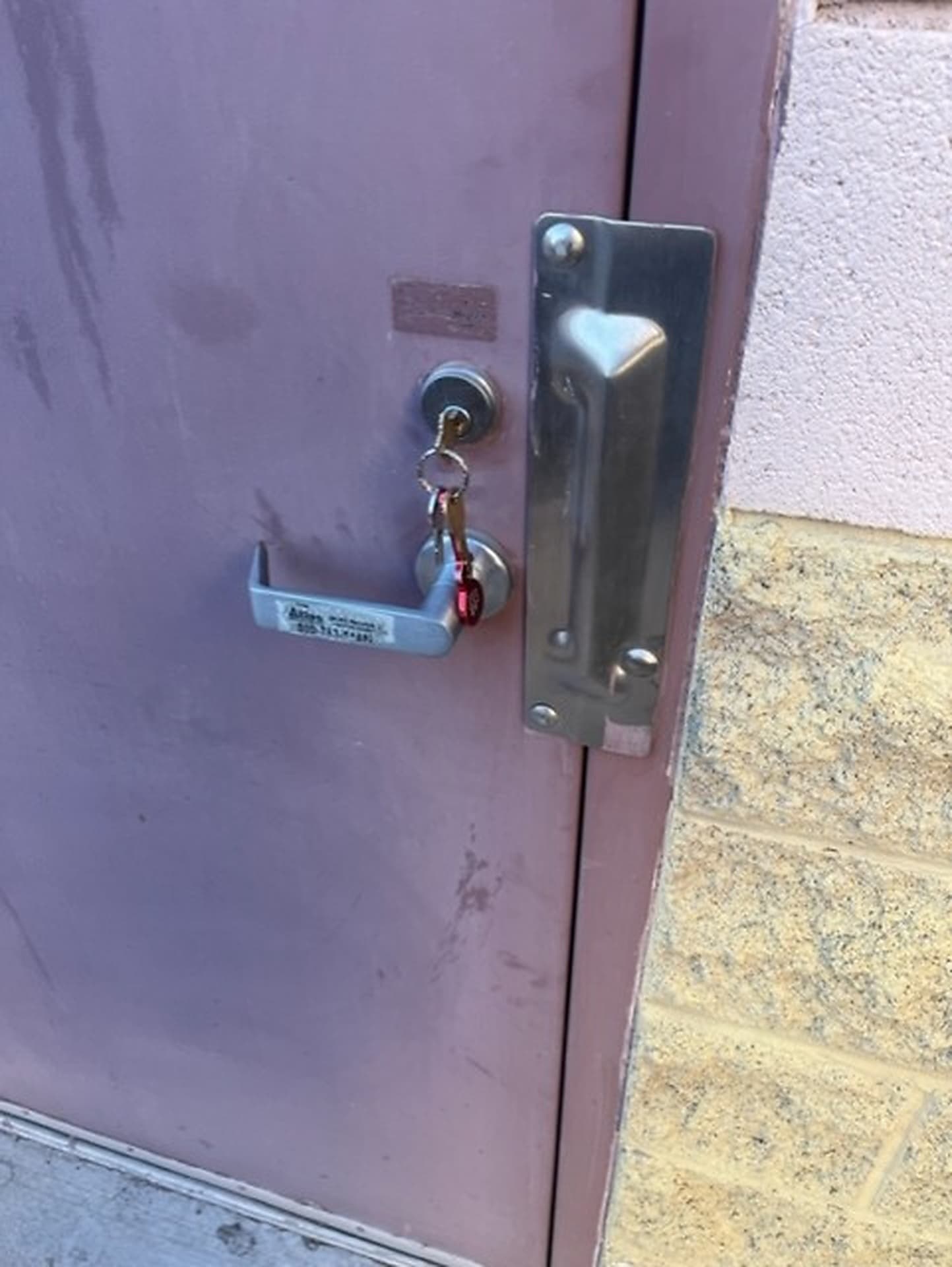 Lever lockset with a key in a door beside a stucco wall