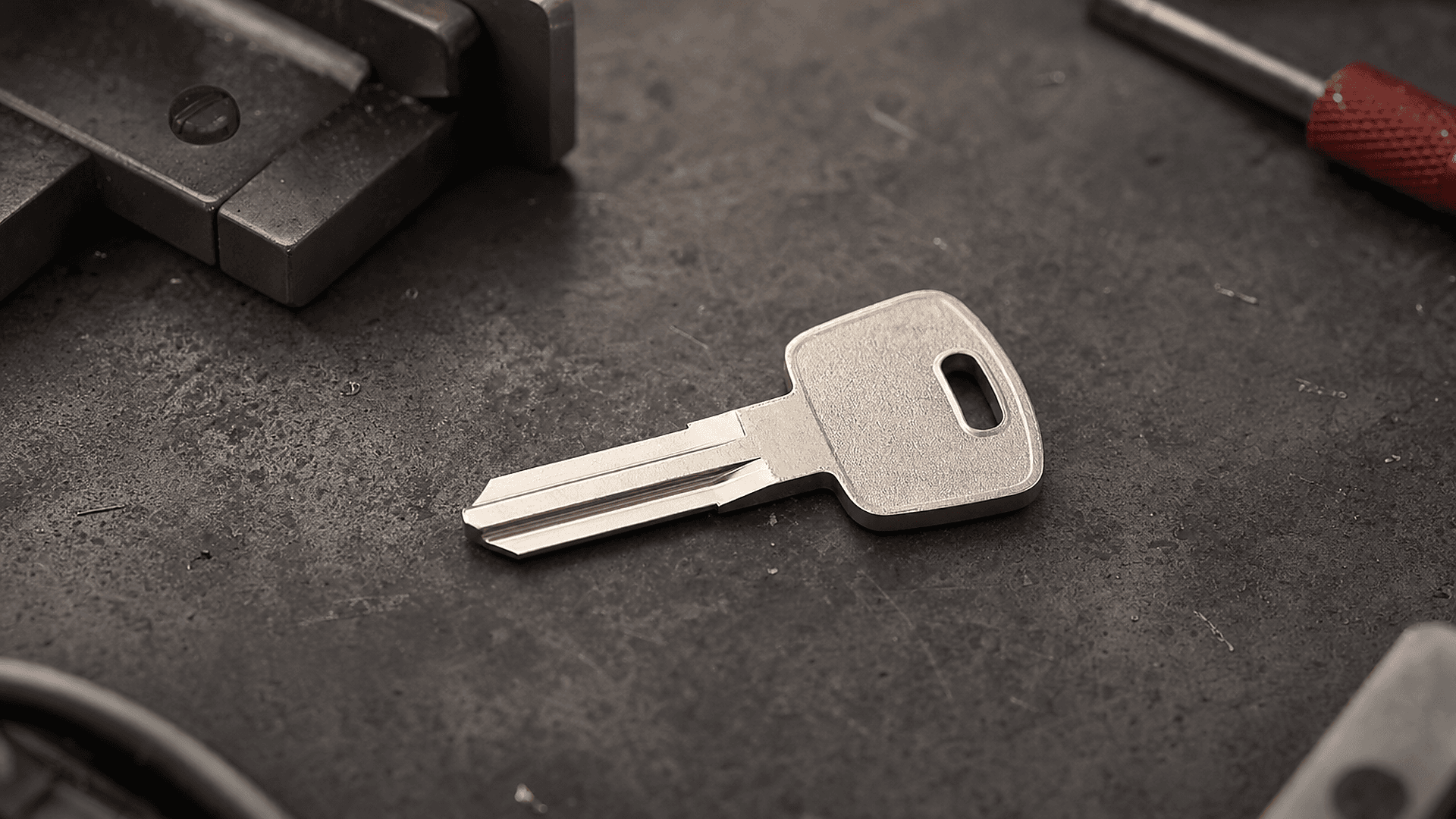 Illustration of a cut metal key resting on a dark workbench beside a vise