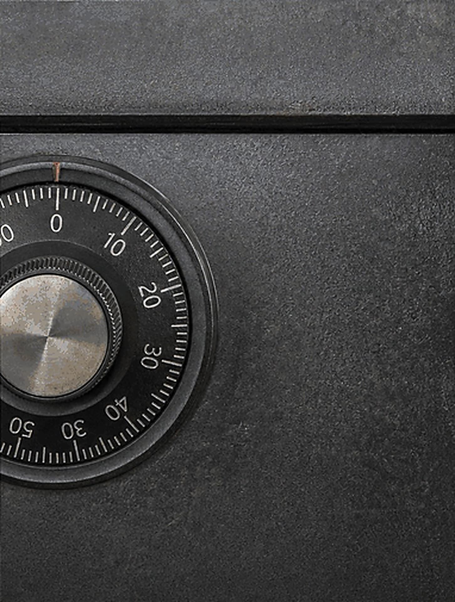 Close-up of a numbered combination dial on a textured black safe door